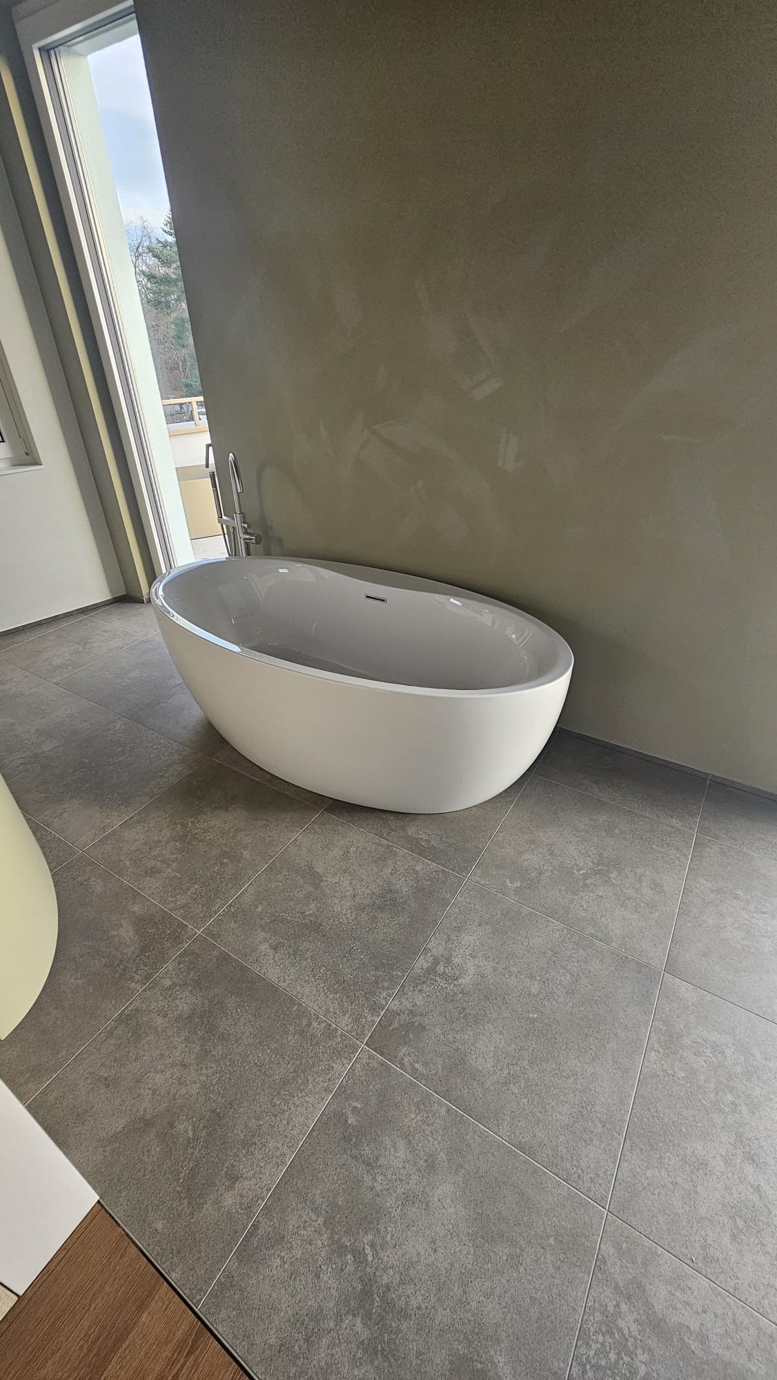 Bad mit freistehender Badewanne und grauen Bodenplatten