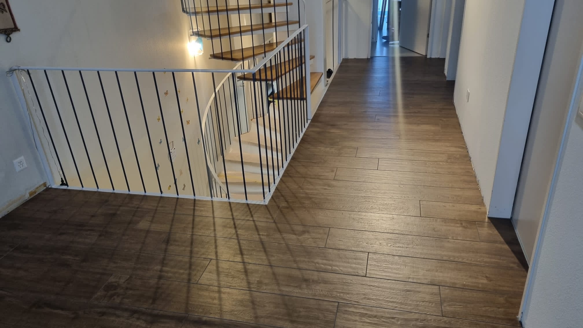 Flur mit Fliesen in Holzoptik und Treppe mit Geländer